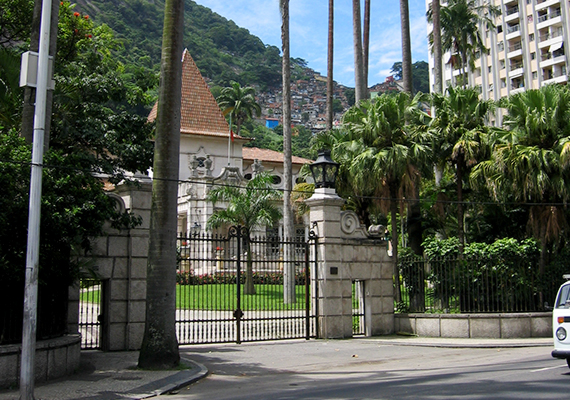 	Első ránézésre szinte csak a pálmafás villát látni a képen, a háttérben azonban feltűnnek Rio de Janeioro nyomornegyedének, a favelának jellegzetes épületei is.