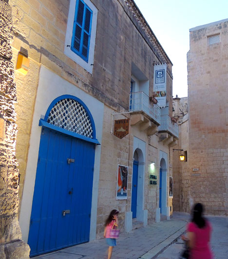 	Egy csipet romantika a Néma Városban	Az egyik legvarázslatosabb hely a szigeten az úgynevezett Néma Város, Valletta határában. A középkori és barokk építészet jegyeinek izgalmas keveredése, a sárga mészkő és az erős kék kontrasztja, a díszes kőfaragások és a merev várfalak váltakozása semmihez sem hasonlítható, megfoghatatlan hangulattal vonja be a történelmi városrészt. Esti kivilágításban mindenképpen megér egy romantikus sétát.